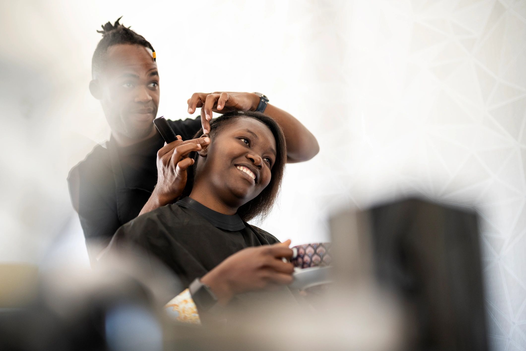 Hair stylist revealing a finished hairstyle to a client in a modern salon